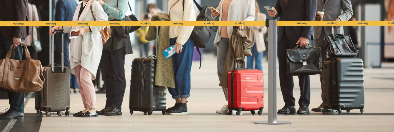 Poste separador Dterminal con cinta personalizada en una cola de aeropuerto
